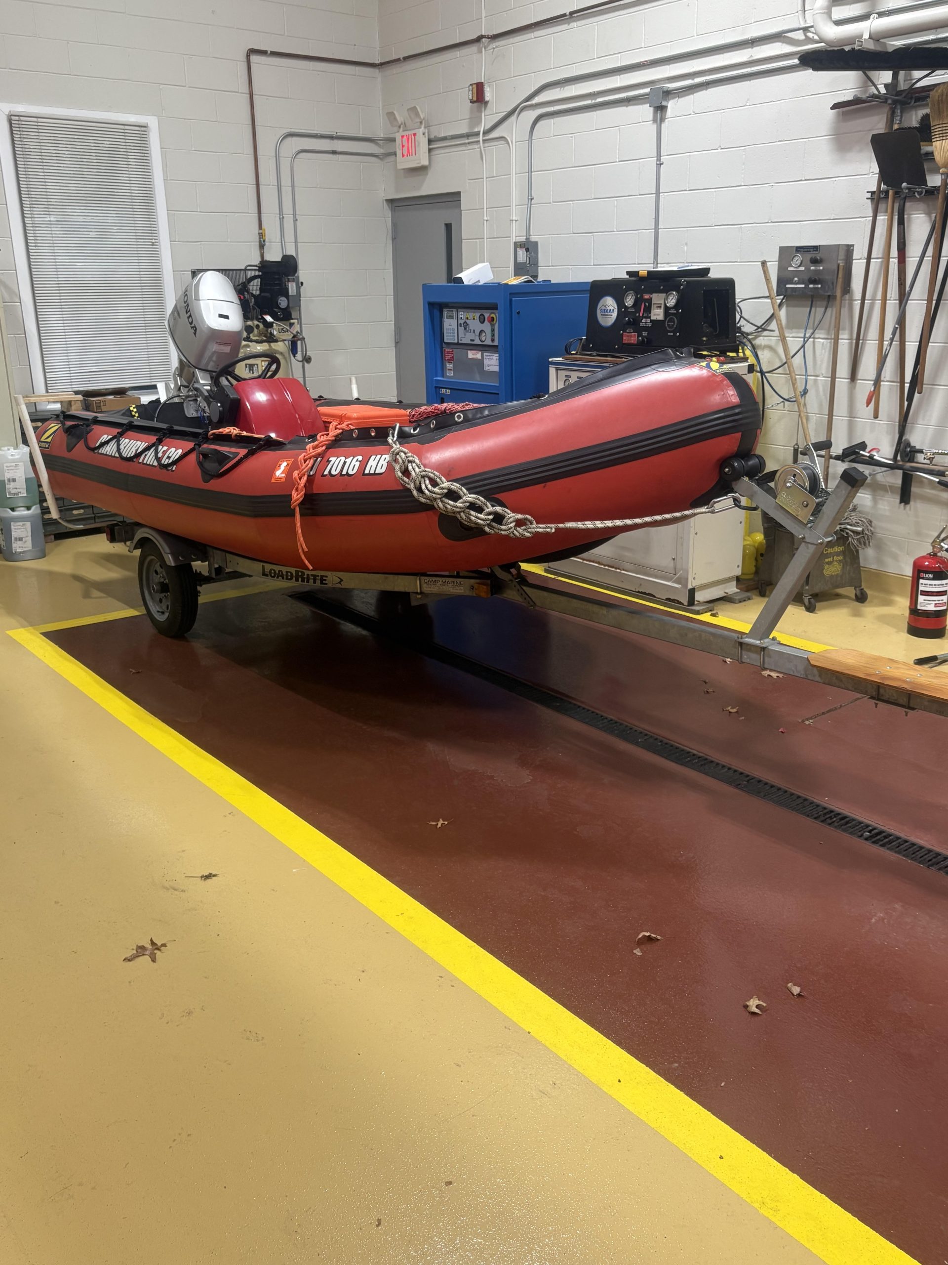 A red inflatable boat with an outboard motor secured on a trailer.